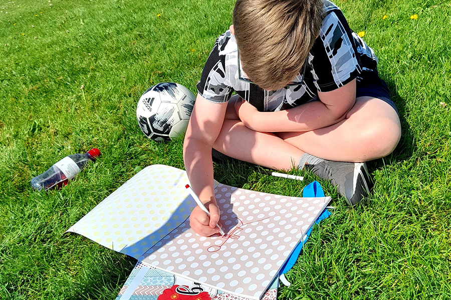 One to one wellbeing session with a young boy. The boy is drawing a superhero which is an interactive Positive Pants workshop.